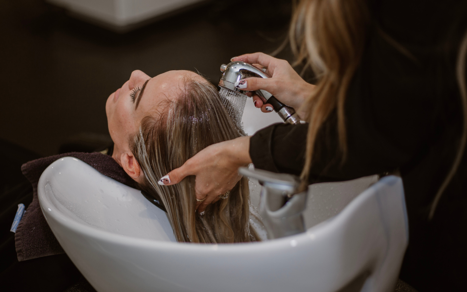 La cliente installée au bac à shampooing, apprécie le moment de rinçage